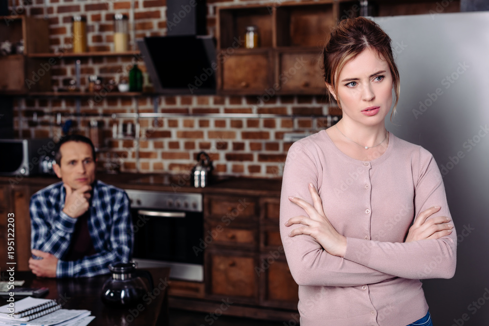 Fototapeta premium selective focus of pensive woman and husband sitting at table at home