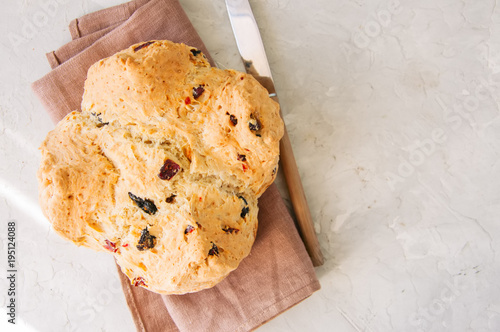 Homemadel Irish soda bread with cranberries and nuts on a napkin on a white stone background. photo