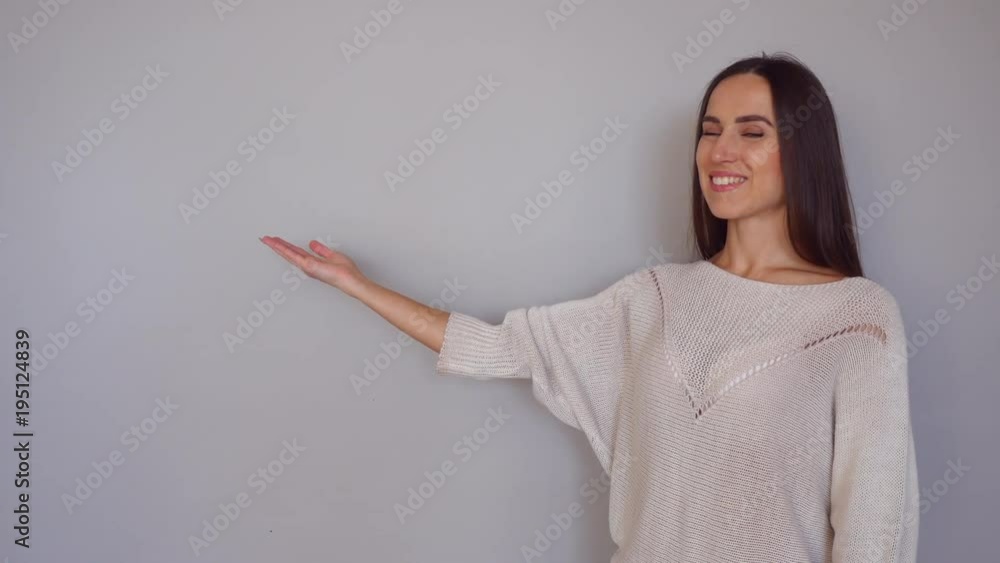 Young woman smiling and indicates with arms on her right to the copy space Young woman smiling and indicates with arms on her right to the copy space