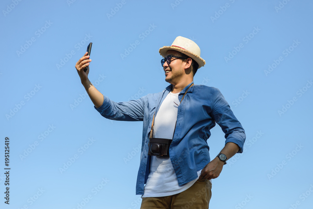 Happy Asian tourist using smartphone selfie himself with blue sky. Happy Asian tourist using smartphone selfie himself with blue sky.