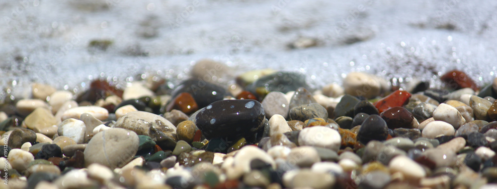Pebbles by sea on beach, for banner and texture. Focus runs through the middle Pebbles by sea on beach, for banner and texture. Focus runs through the middle