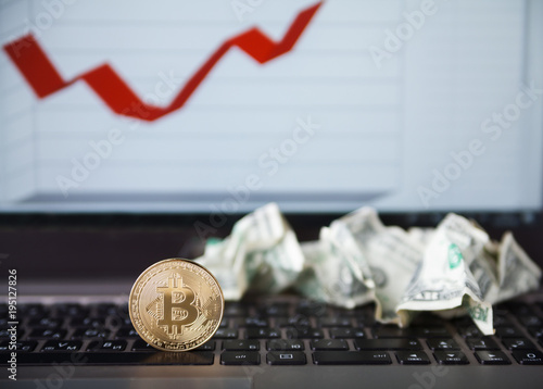 Gold bitcoins and crumpled dollars on laptop
