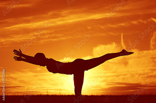 Fototapeta Naklejka Na Ścianę i Meble -  Silhouette of a young girl yoga pose sunset sport