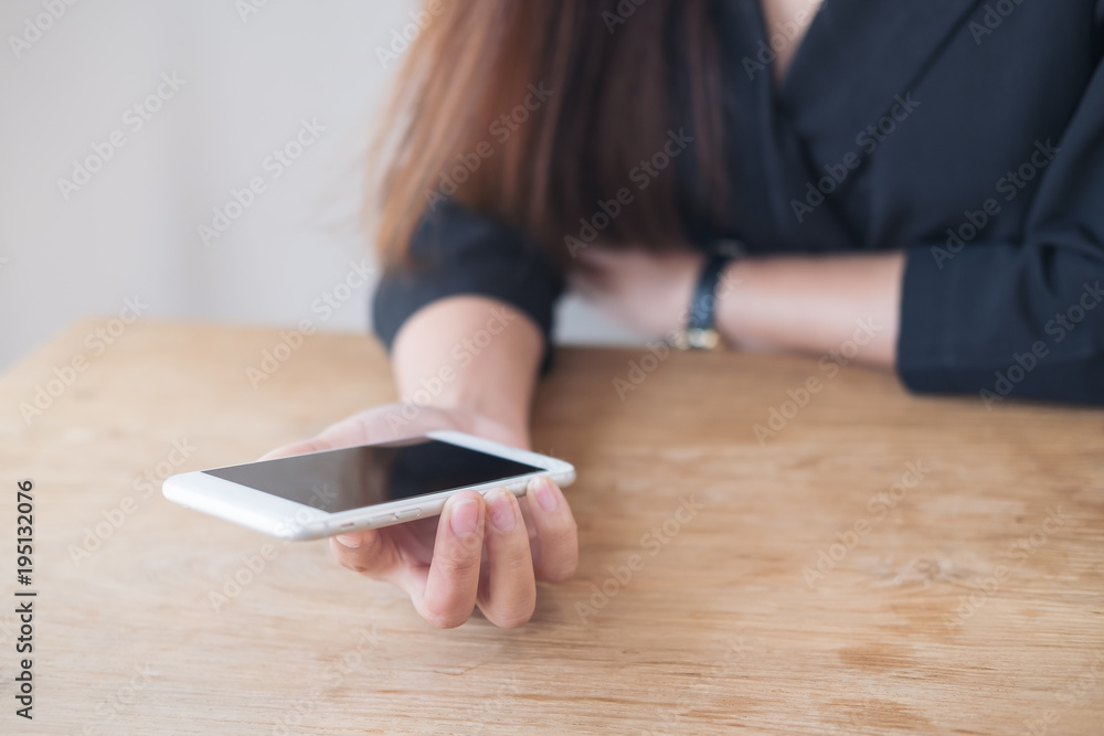 Closeup image of woman's hands holding white mobile phone on wooden table Closeup image of woman's hands holding white mobile phone on wooden table