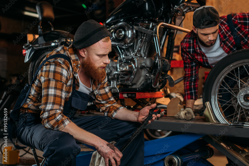 handsome mechanics working together at custom garage handsome mechanics working together at custom garage