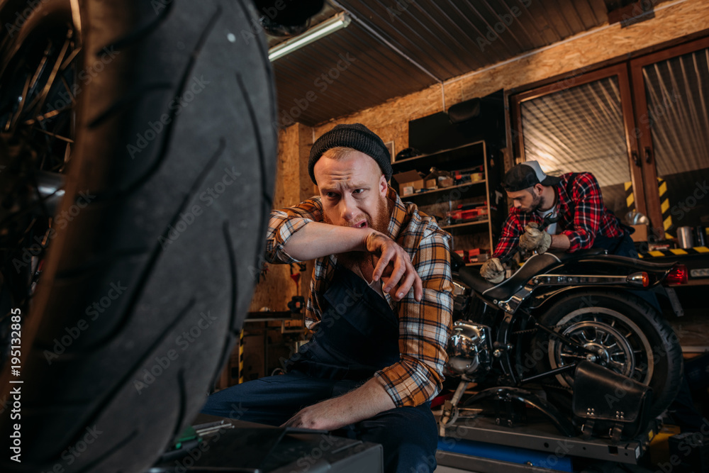 exhausted mechanic wiping sweat after work at garage