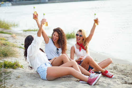 Group of young female friends sitting on the beach and having fun.