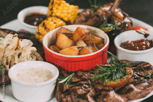 close-up view of grilled vegetables, roasted chicken wings and beef steaks with potatoes on plate