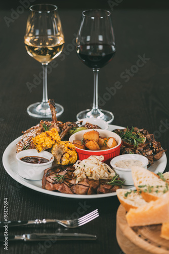 glasses of wine and plate with grilled vegetables and meat on table in restaurant