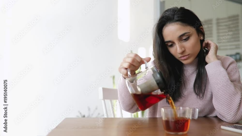 Beautiful woman pouring tea from kettle into glass in a cafe Beautiful woman pouring tea from kettle into glass in a cafe