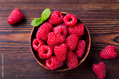 Raspberries in bowl on wooden table. Top view.