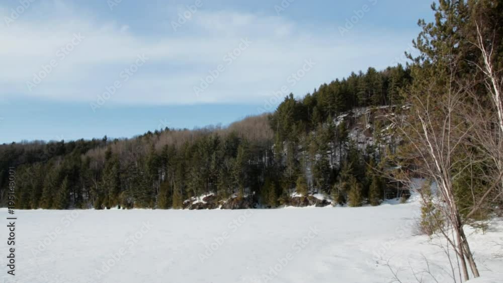Wind blowing on clouds and tree branches by frozen lake and hill. Wind blowing on clouds and tree branches by frozen lake and hill.