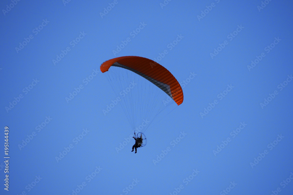 Paraglider flies in blue skies. The glider is a light aircraft plans in the air. Paraglider flies in blue skies. The glider is a light aircraft plans in the air.