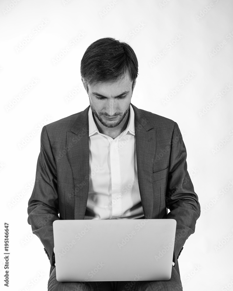 Successful businessman is sitting and working with laptop. Light background. Successful businessman is sitting and working with laptop. Light background.