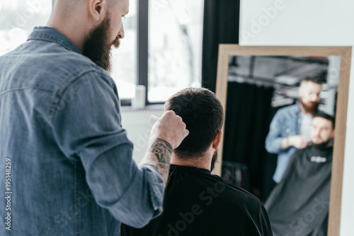 rear view of barber combing customer hair at barbershop