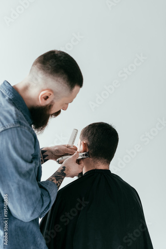 rear view of barber shaving customer hair at barbershop isolated on white