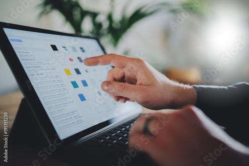 Closeup shot of male hands using modern digital tablet at new loft, businessman working on portable computer at office, technology and communication concept, flare light photo