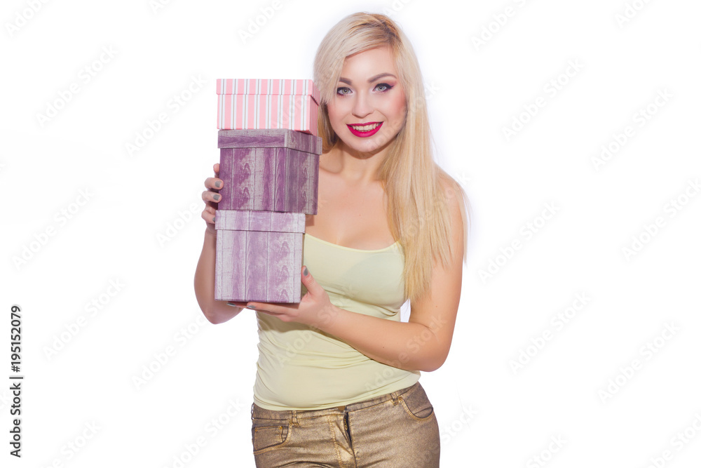 Studio photo of a beautiful young blond woman with long hair dressed in a summer light yellow jersey and golden jeans. The girl is holding boxes with gifts. A model poses against a white background. Studio photo of a beautiful young blond woman with long hair dressed in a summer light yellow jersey and golden jeans. The girl is holding boxes with gifts. A model poses against a white background.