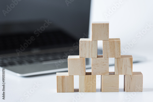 stack of wood cube building blocks with laptop computer  background
