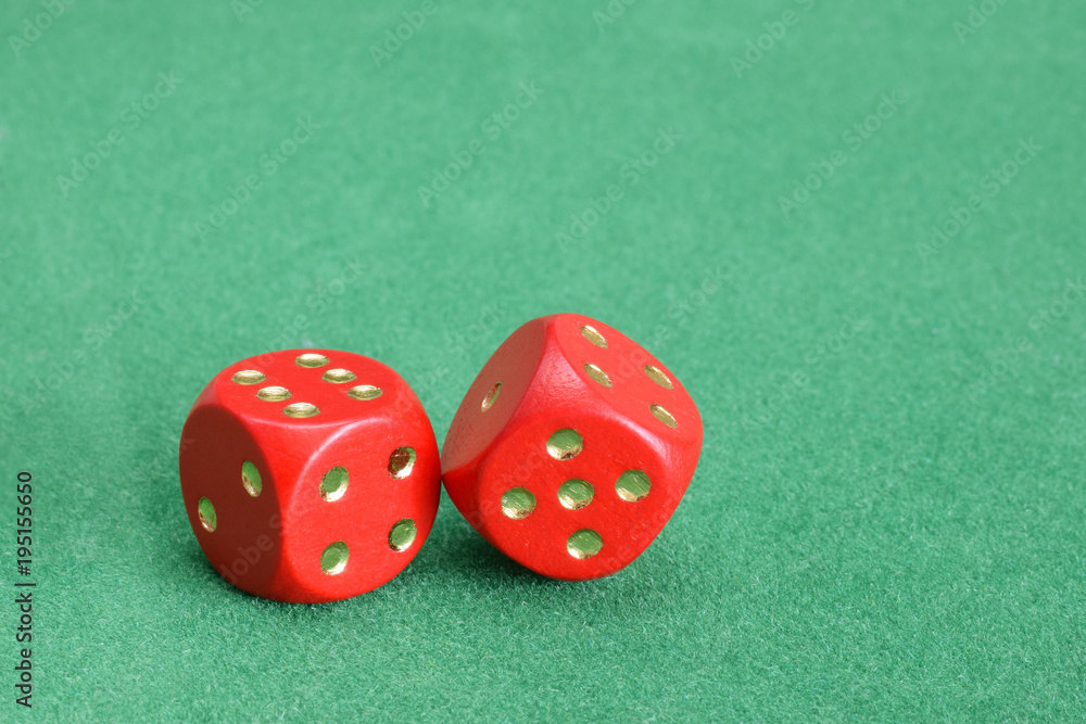 Red dice with golden points on green velvet table Red dice with golden points on green velvet table