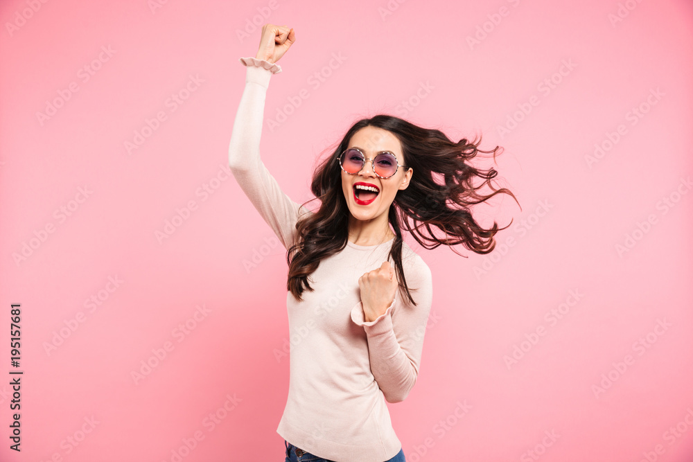 Image of cheerful woman 20s in casual clenching fists with delight and smile, isolated over pink background Image of cheerful woman 20s in casual clenching fists with delight and smile, isolated over pink background