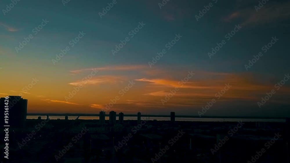 A city sits silhouetted against a beautiful deep orange sunset along the horizon during dusk A city sits silhouetted against a beautiful deep orange sunset along the horizon during dusk