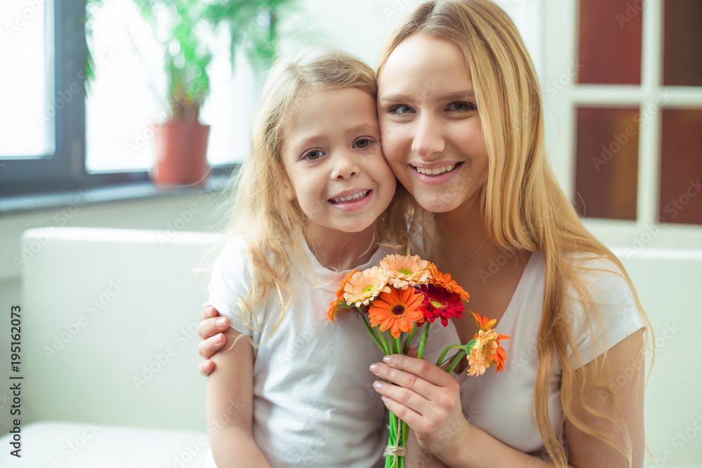 Beautiful cheerful mother and a little smiling daughter embrace with gifts in their hands and look at the camera. Birthday. March 8. Women's Day. Beautiful cheerful mother and a little smiling daughter embrace with gifts in their hands and look at the camera. Birthday. March 8. Women's Day.