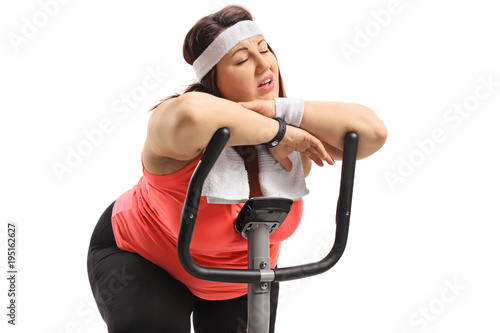 Tired overweight woman sleeping on an exercise bike