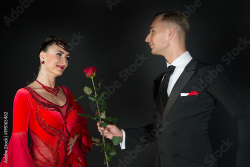 Man give rose flower to happy woman in red dress