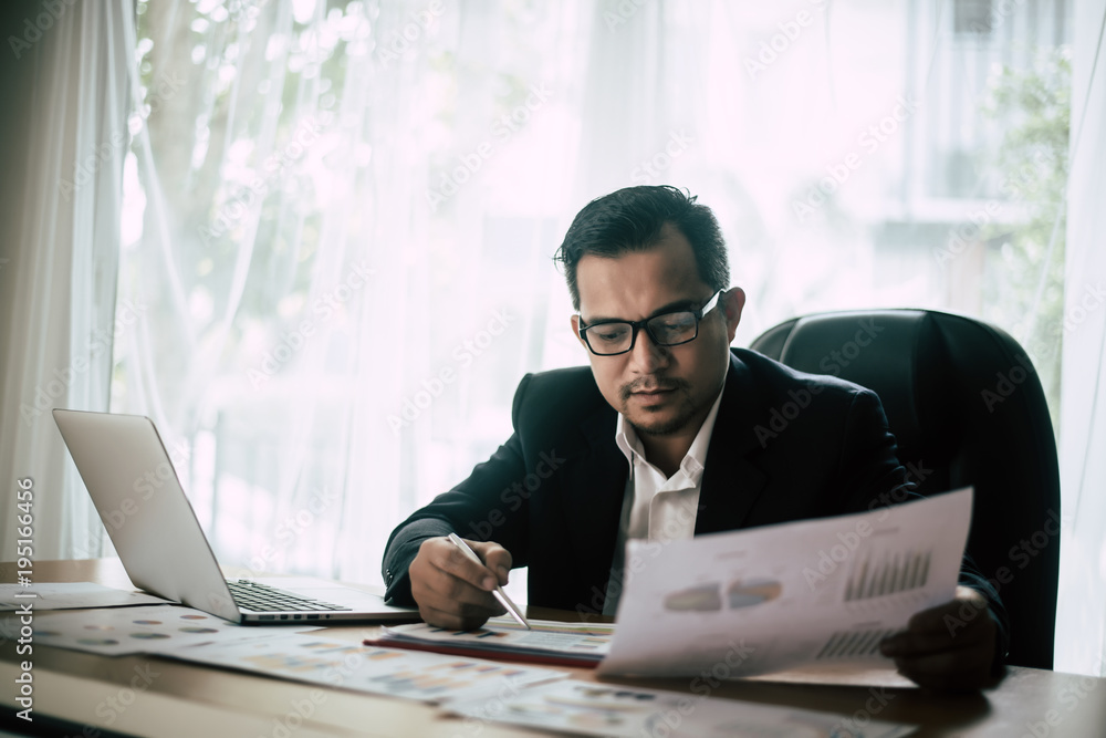 Businessman sitting at his workplace in front of laptop computer while doing some business paperwork. Businessman sitting at his workplace in front of laptop computer while doing some business paperwork.
