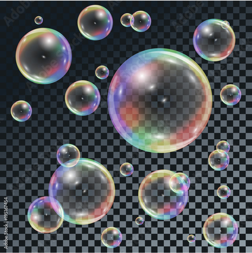Soap transparent bubbles with rainbow reflection on dark checkered background.