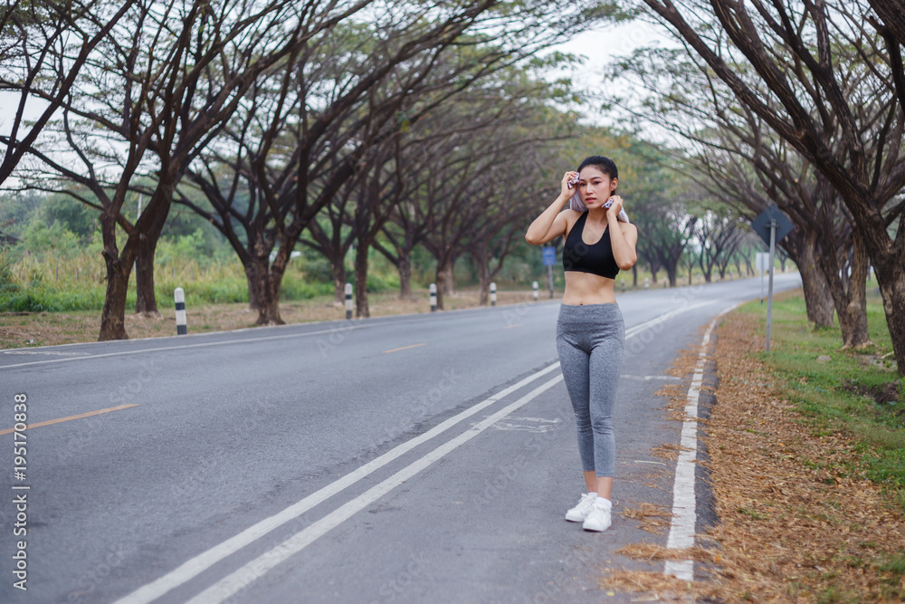 young sporty woman resting and wiping her sweat with a towel after workout sport exercises outdoors at park young sporty woman resting and wiping her sweat with a towel after workout sport exercises outdoors at park