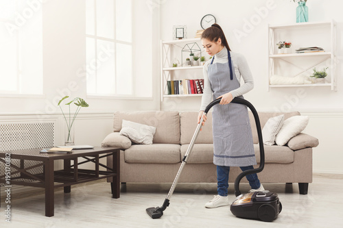 Young woman cleaning house with vacuum cleaner