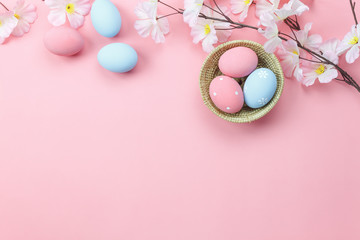 Table top view shot of arrangement decoration Happy Easter holiday background concept.Flat lay colorful bunny eggs with spring floral on modern beautiful pink paper at office desk.Design pastel tone.