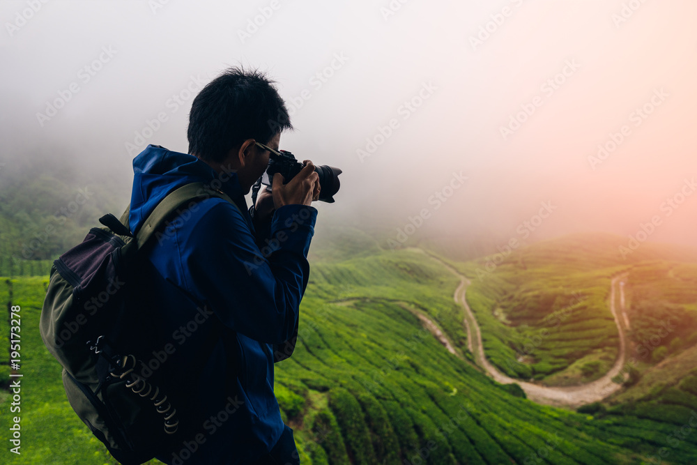 Young asian backpacker traveling into tea fields with mist. Young man traveler take a photo of mountain tea field with foggy, Enjoying tea plantations in Cameron Highlands near Kuala lumpur Malaysia Young asian backpacker traveling into tea fields with mist. Young man traveler take a photo of mountain tea field with foggy, Enjoying tea plantations in Cameron Highlands near Kuala lumpur Malaysia