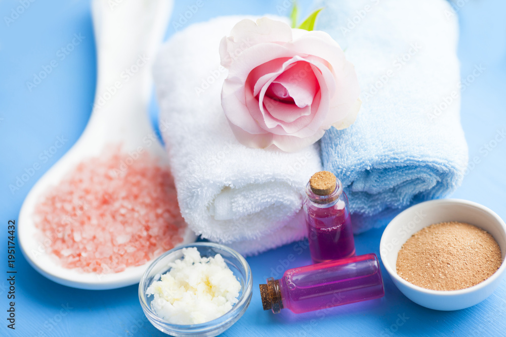 Spa and natural cosmetics concept. Set of sea salt, rose, natural clay ,shea oil, glass bottles and other spa treatment tools on the blue wooden background. Top view. Space for a text. Close up. Spa and natural cosmetics concept. Set of sea salt, rose, natural clay ,shea oil, glass bottles and other spa treatment tools on the blue wooden background. Top view. Space for a text. Close up.