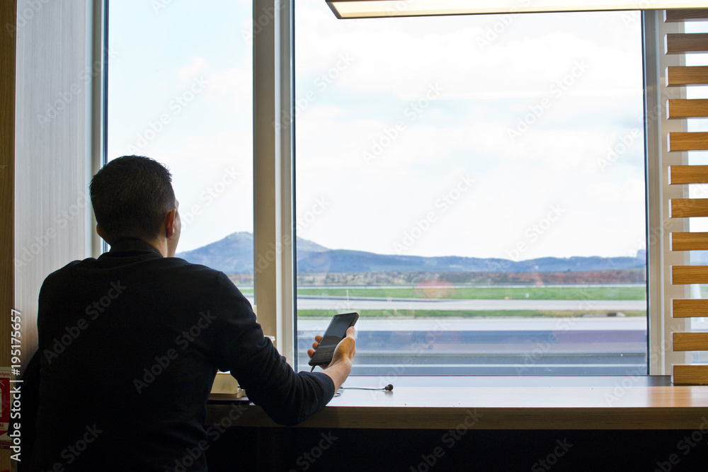 Fototapeta premium A man with a smartphone waiting for the plane, flight at the airport