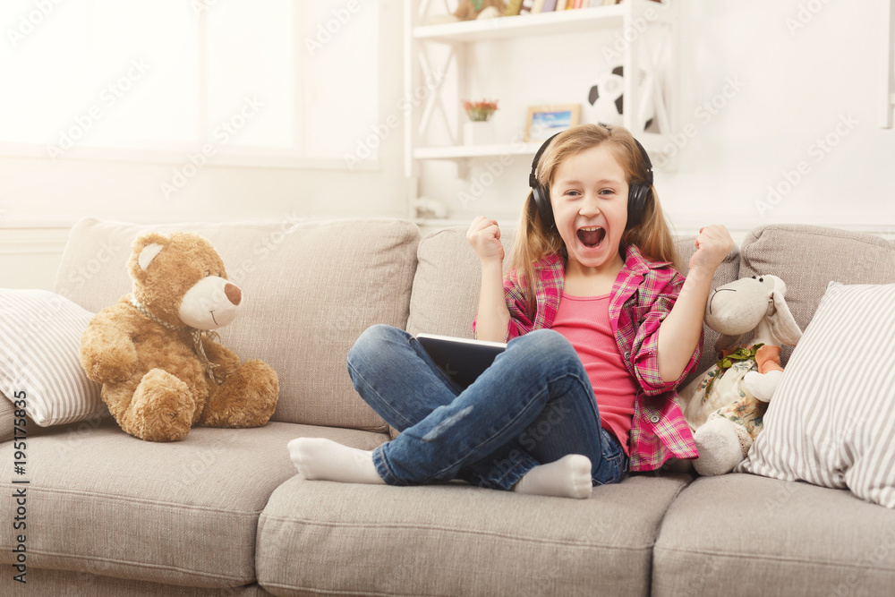 Little girl in headphones with tablet at home