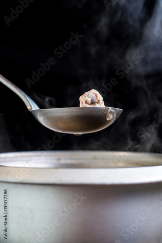 Pork rip in soup scoop with Stainless hot pot, water drop, onion and vapour on black background, Asian food, Copy space