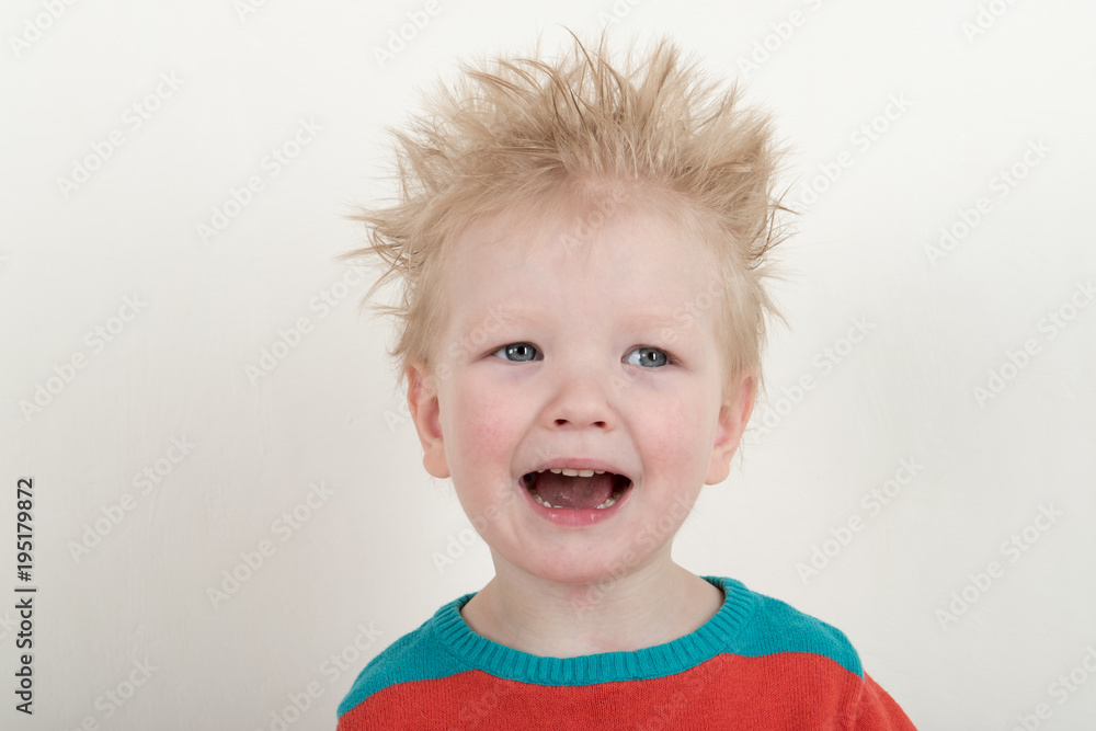 Naklejka premium Happy Caucasian blonde with microphone. Drummer play on a new drum kit. Parents bought a drum box for training. Child in bright clothes with new chopsticks in hands happy at home. Bright emotions