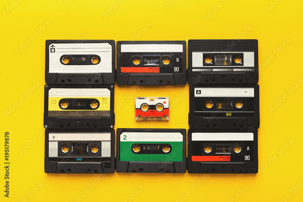 Big retro cassettes framing a small one on yellow background, top view, copy space Big retro cassettes framing a small one on yellow background, top view, copy space