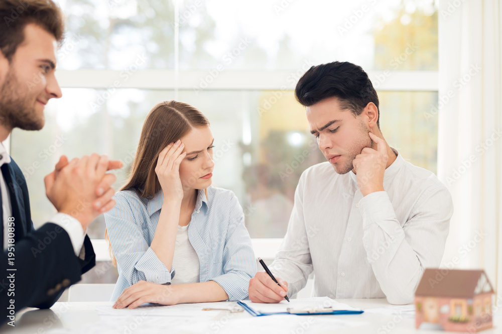 Young couple in a meeting with a realtor. Guy and girl make a contract with realtor buying property. Young couple in a meeting with a realtor. Guy and girl make a contract with realtor buying property.