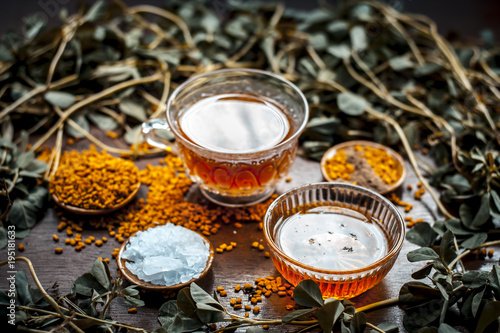 Close up of fenugreek tea with honey,lemon,sugar and fenugreek seeds on a wooden surface in dark Gothic colors.It helps to soothe menstrual cramps, lower blood sugar, promote proper digestion, etc. photo