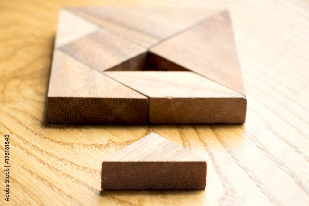 Tangram puzzle in square shape that wait for complete on wood background