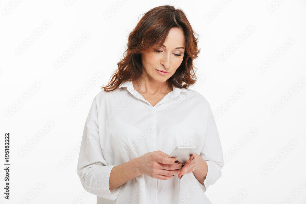 Portrait of modern woman 40s holding smartphone and browsing internet or social networks, isolated over white background in studio Portrait of modern woman 40s holding smartphone and browsing internet or social networks, isolated over white background in studio