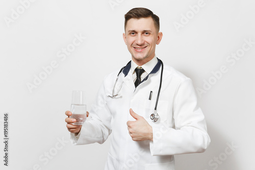 Smiling handsome young doctor man showing thumbs up isolated on white background. Male doctor in medical uniform, stethoscope holding glass of clear water. Healthcare personnel health medicine concept