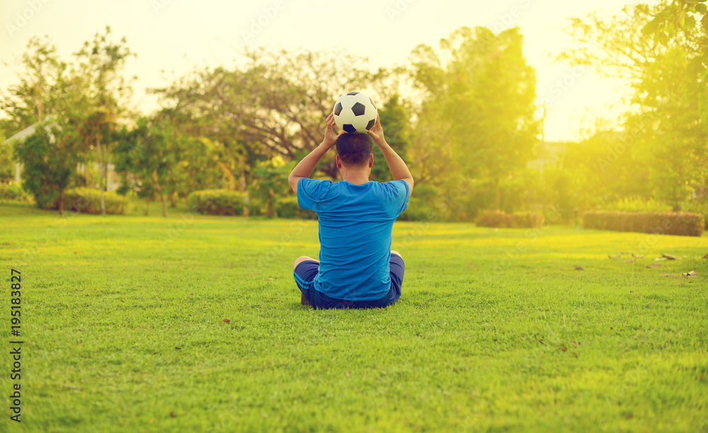 Asian man playing football alone in garden
Asian man playing football alone in garden