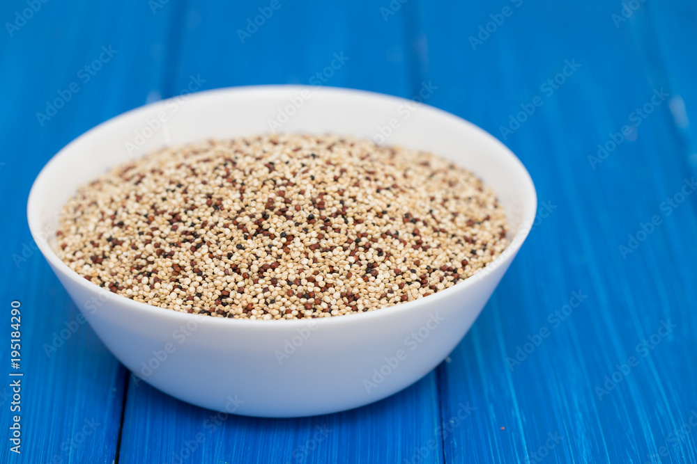 uncooked quinoa in white bowl on wooden background uncooked quinoa in white bowl on wooden background
