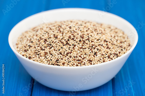 uncooked quinoa in white bowl on wooden background