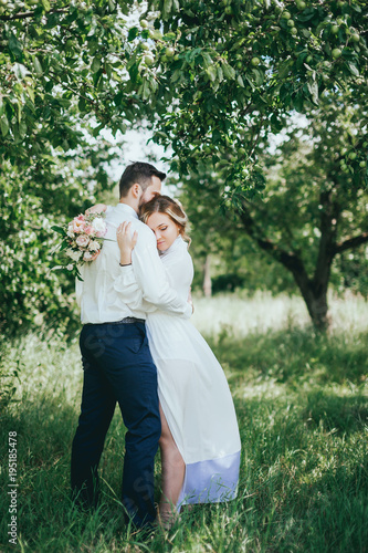 stylish groom with a beard and groom in the garden. fine art style. rustic